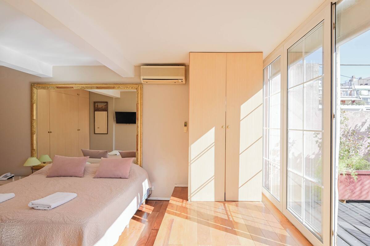 A bedroom with a bed, a large mirror, an air conditioning unit, and a sliding glass door to the outside.