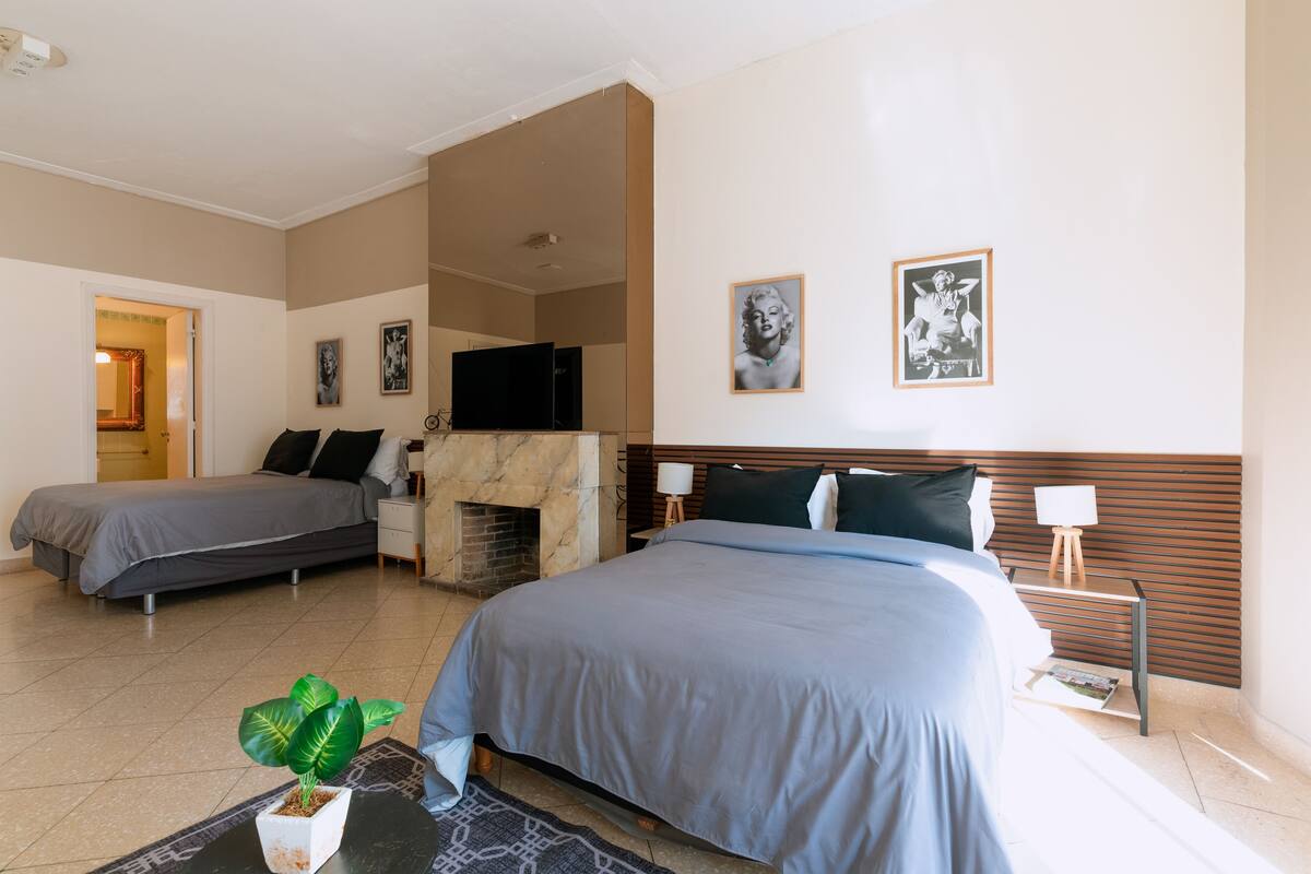 Ein Hotelzimmer mit zwei Betten, einem Kamin, einem Fernseher und Kunstwerken an den Wänden.