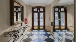 A hallway with a checkered floor, a marble bench, and a large mirror on the wall. - Leonardo Da Vinci Aparts by MOT Rentals (Buenos Aires)
