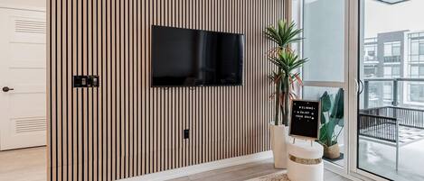 Una habitación moderna con una pared de madera con listones, un televisor de pantalla plana y un cartel de bienvenida.