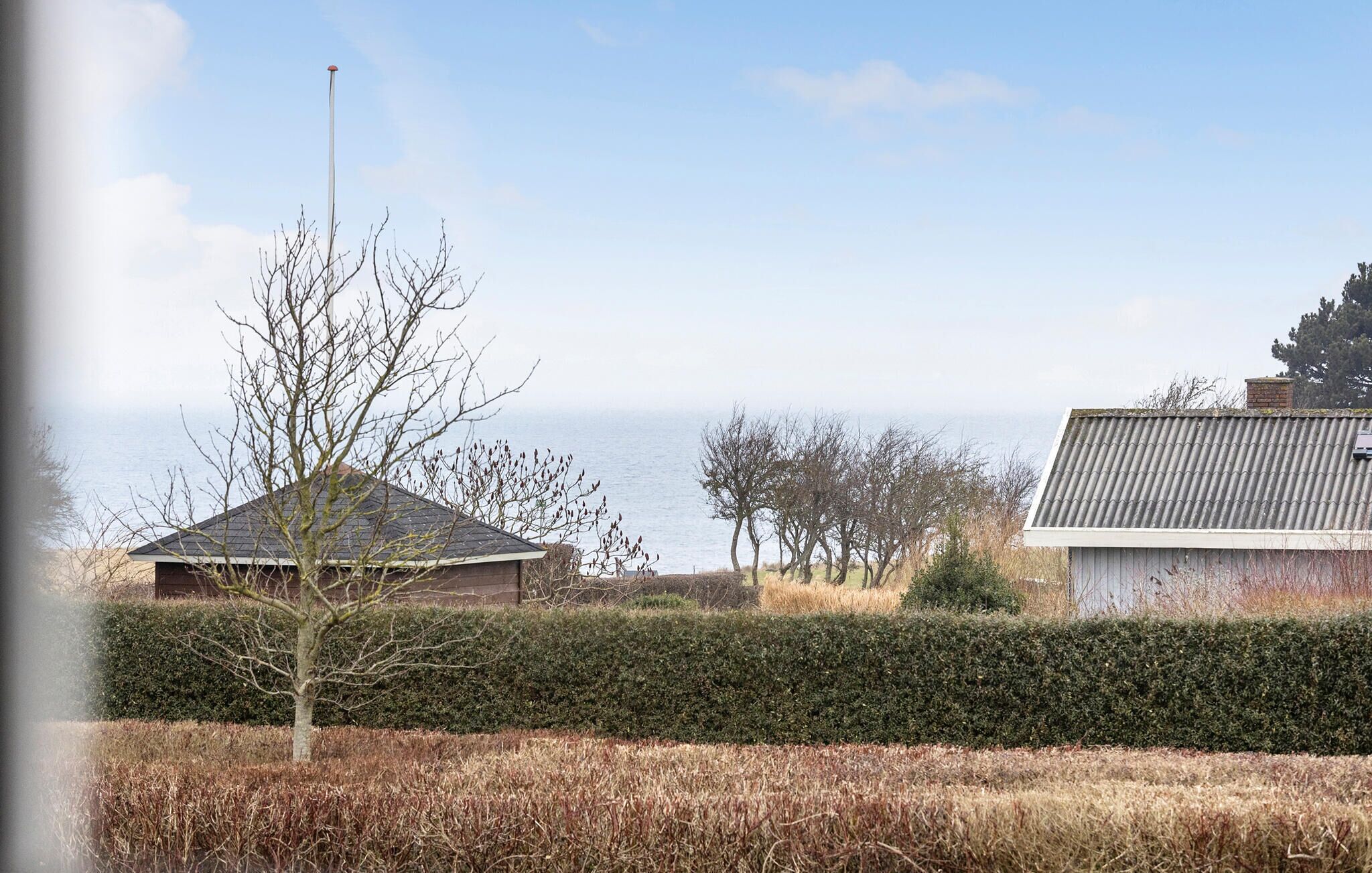 A coastal property with a house, a tree, and a view of the sea.