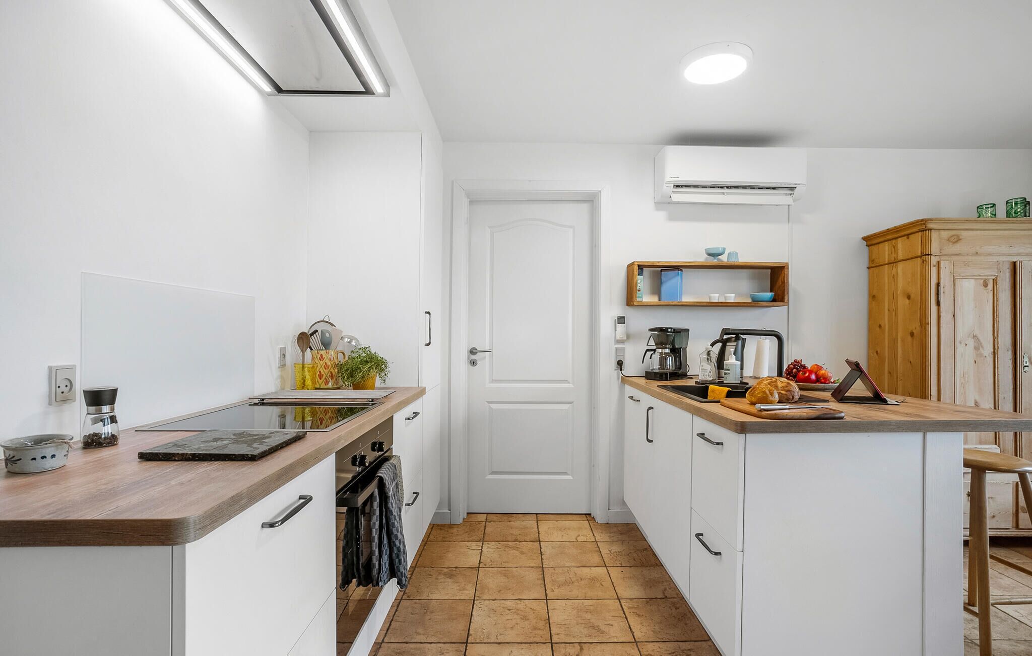 A compact kitchen with white cabinets, a wooden countertop, and a tiled floor.