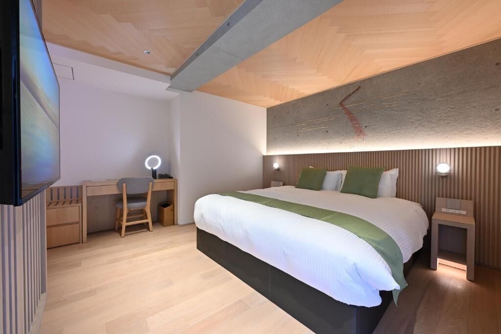 Ein modernes Schlafzimmer mit einem großen Bett, Nachttischen, einem Schreibtisch und einem Sessel.