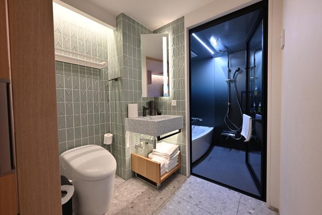 Et moderne badeværelse med toilet, håndvask og bruser.