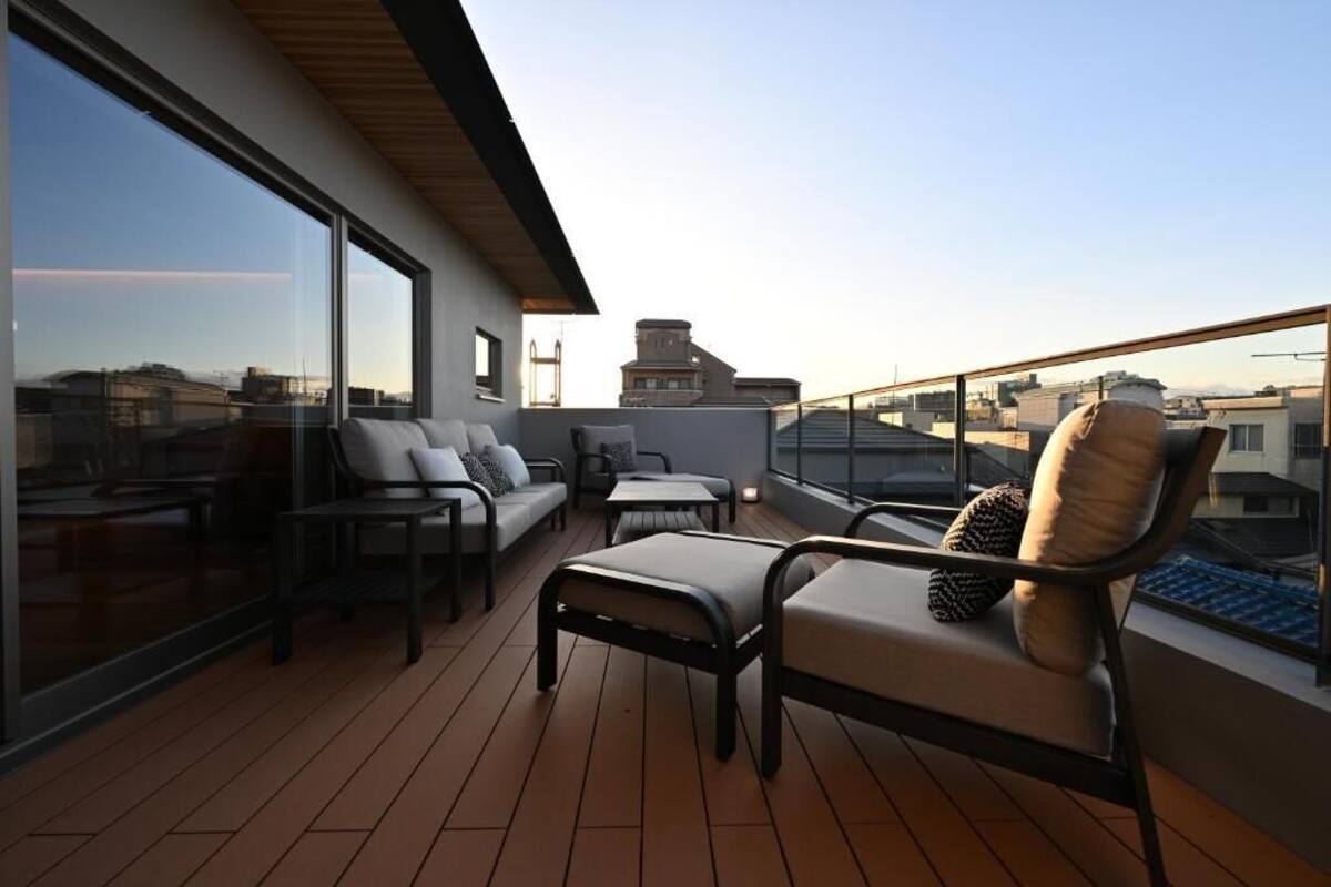 A rooftop terrace with a sofa, chairs, and a table.