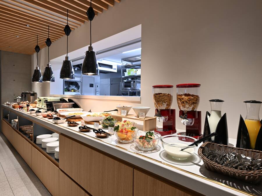 A buffet with various food items, a coffee machine, and beverage dispensers.