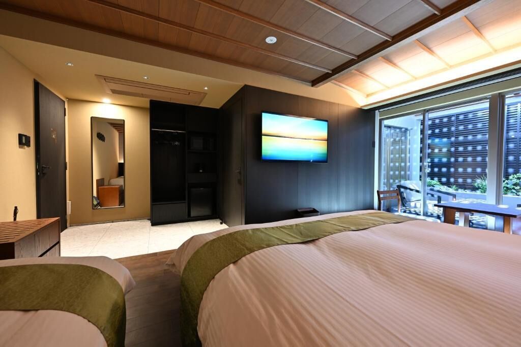 A hotel room with a bed, a TV, a balcony, and a view of the city.