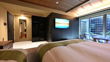 A hotel room with a bed, a TV, a balcony, and a view of the city.