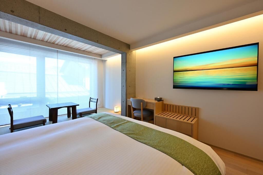 Una habitación de hotel con una cama grande, un escritorio, una silla y un televisor en la pared.