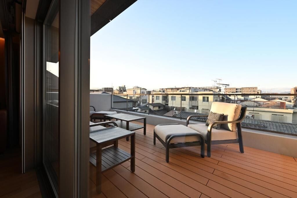 A balcony with wooden flooring, a sofa, and a table.