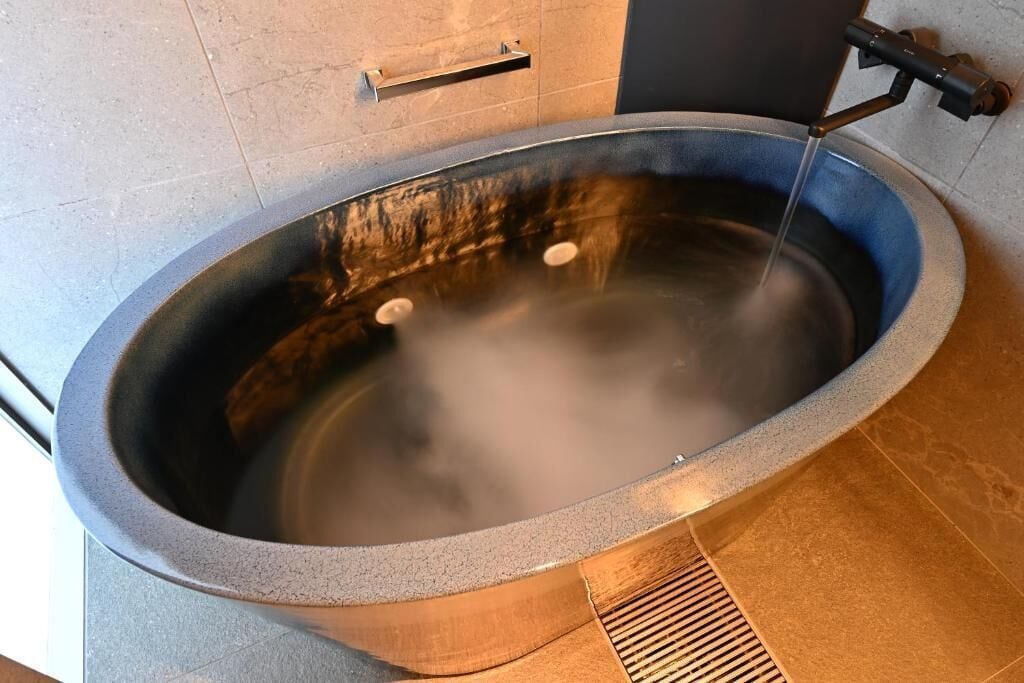 A hot tub with a metal frame and a blue interior, set against a tiled wall.