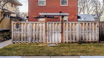 A red brick house with a wooden fence and a wooden pergola.