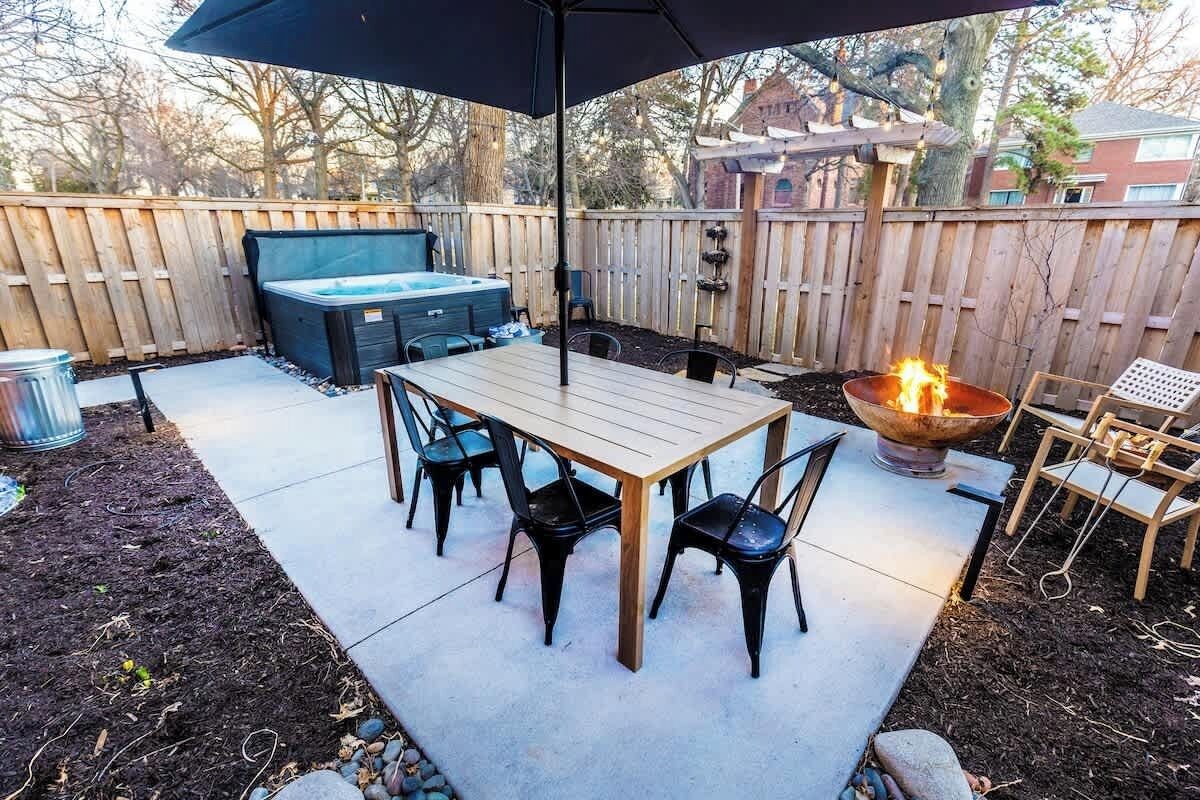 Een buitenpatio met een tafel, stoelen, een jacuzzi en een vuurkuil.