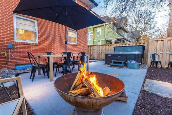 Ein Garten mit Feuerstelle, Sitzgelegenheiten und Grill.