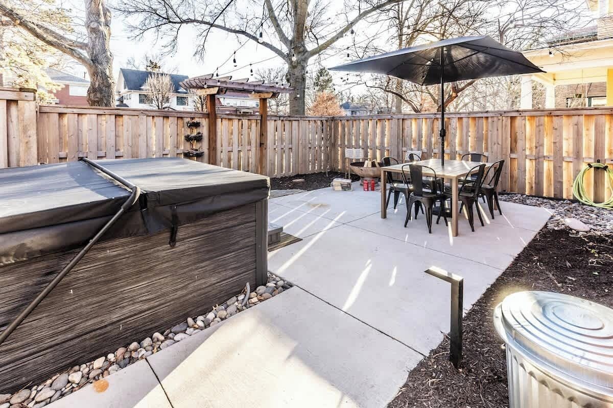 Une terrasse à l’arrière de la maison, équipée d’un barbecue, d’une table à manger et de chaises.