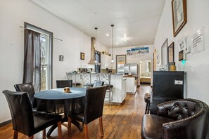 Un comedor con una mesa redonda, sillas negras y una cocina al fondo.