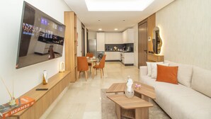 Una sala de estar moderna con un televisor de pantalla plana, un sofá, una mesa de centro y un comedor con sillas y una mesa.