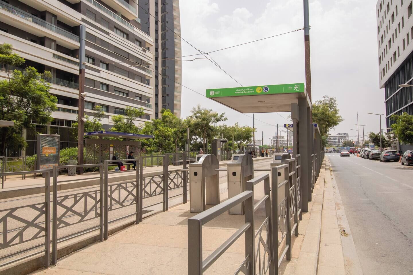 Une scène urbaine moderne avec un passage piéton, un arrêt de bus et de grands immeubles.