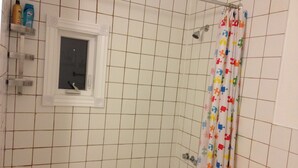 A bathroom with a bathtub, a shower curtain with puzzle pieces, and a window with a view.