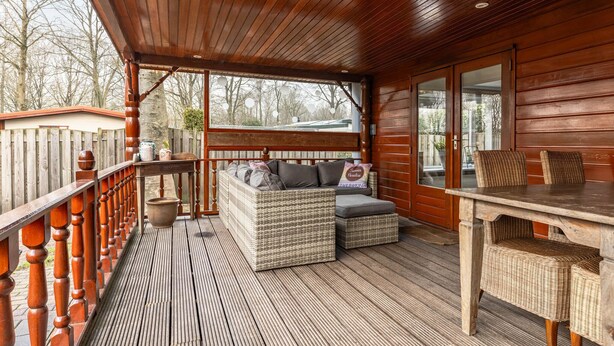 Eine Holzterrasse mit Korbmöbeln, einem Tisch und Blick auf die Umgebung.
