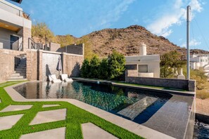 Una casa moderna amb piscina, escales de pedra i vistes a una muntanya.