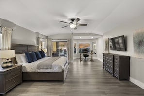 Ein Schlafzimmer mit Bett, Nachttisch, Lampe und Deckenventilator.