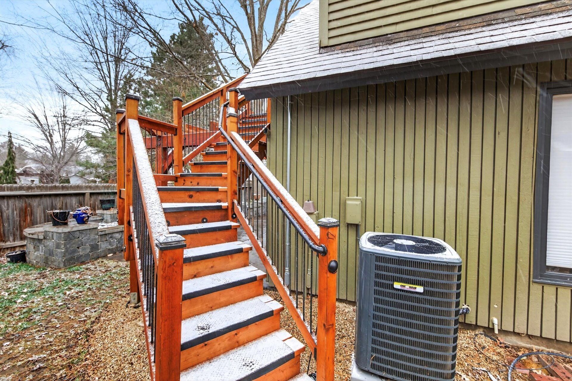 A wooden staircase with a metal railing leading to a house.