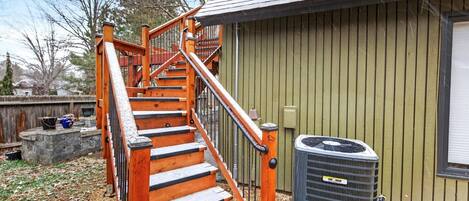 A wooden staircase with a metal railing leading to a house.