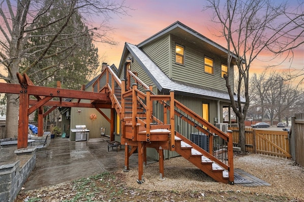 Une maison à deux étages avec un escalier en bois et un patio couvert.