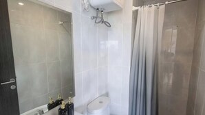 A modern bathroom with a white sink, toilet, and shower curtain. - Mashley Room at Serpong Garden Apartment (Cisauk)
