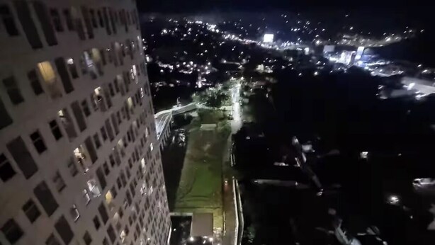 A nighttime view of a high-rise building with a pool and a bridge. - Mashley Room at Serpong Garden Apartment (Cisauk)