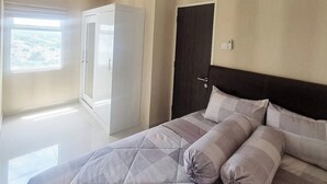 A bedroom with a large bed, a wardrobe, a door, and a ceiling light. - Mashley Room at Serpong Garden Apartment (Cisauk)