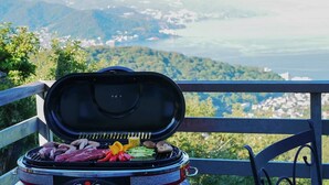 A portable grill with various meats and vegetables on a balcony overlooking a scenic landscape. - Izu-atami Ocean View House (Atami)