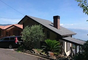 A house with a sloped roof, a chimney, and a view of the water. - Izu-atami Ocean View House (Atami)