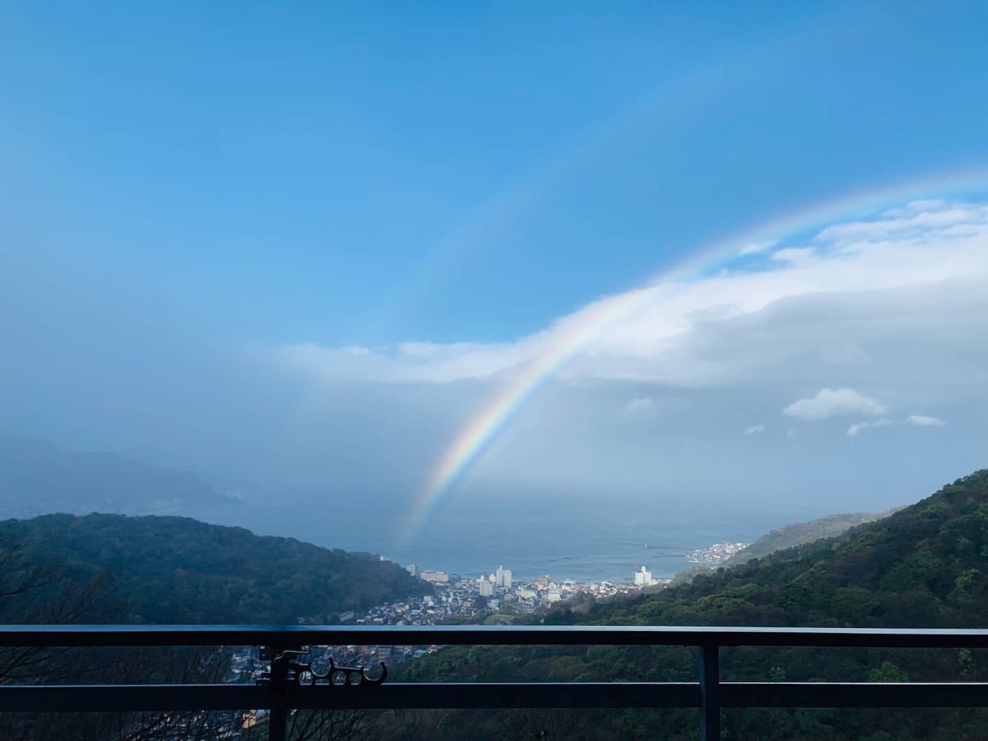 A cityscape with a rainbow over mountains.