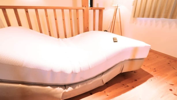 A bed with a wooden headboard, a bedside lamp, and a window with curtains. - Izu-atami Ocean View House (Atami)