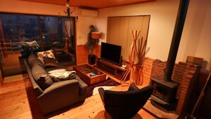A cozy living room with a sofa, coffee table, TV, and fireplace. - Izu-atami Ocean View House (Atami)
