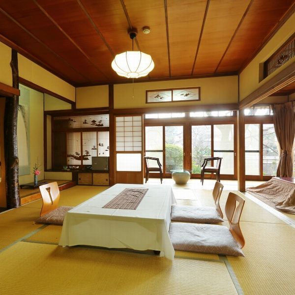 Una habitación japonesa tradicional con suelo de tatami, una mesa baja y puertas correderas.