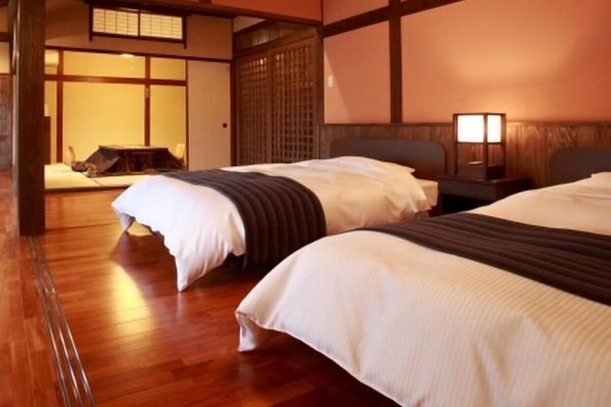 A traditional Japanese-style bedroom with two beds, wooden flooring, and a sliding door.