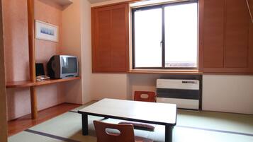 Una habitación con suelo de tatami, una mesa baja, un televisor y una puerta corredera.