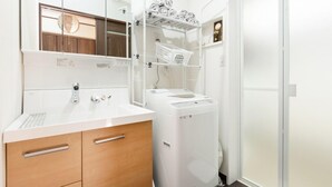 Ein modernes Badezimmer mit Waschbecken, Holzschrank und integrierter Waschmaschine.