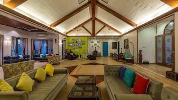 A spacious living room with high ceilings, multiple seating areas, and a green accent wall with framed pictures.