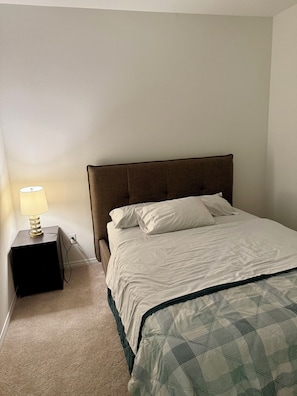 Een slaapkamer met een bed, een nachtkastje met een lamp en een stopcontact.