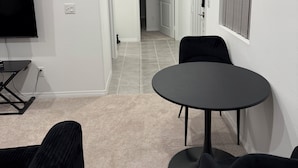 Un salon moderne avec un téléviseur à écran plat, une table ronde et deux chaises noires.