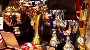 A display of trophies and medals, including a large gold trophy and several silver ones, with labels indicating they are from the FIS-RACE Snowboard 2017 Pielders 2 and 3 Platz. - Guesthouse Curry Village (Kiryu)