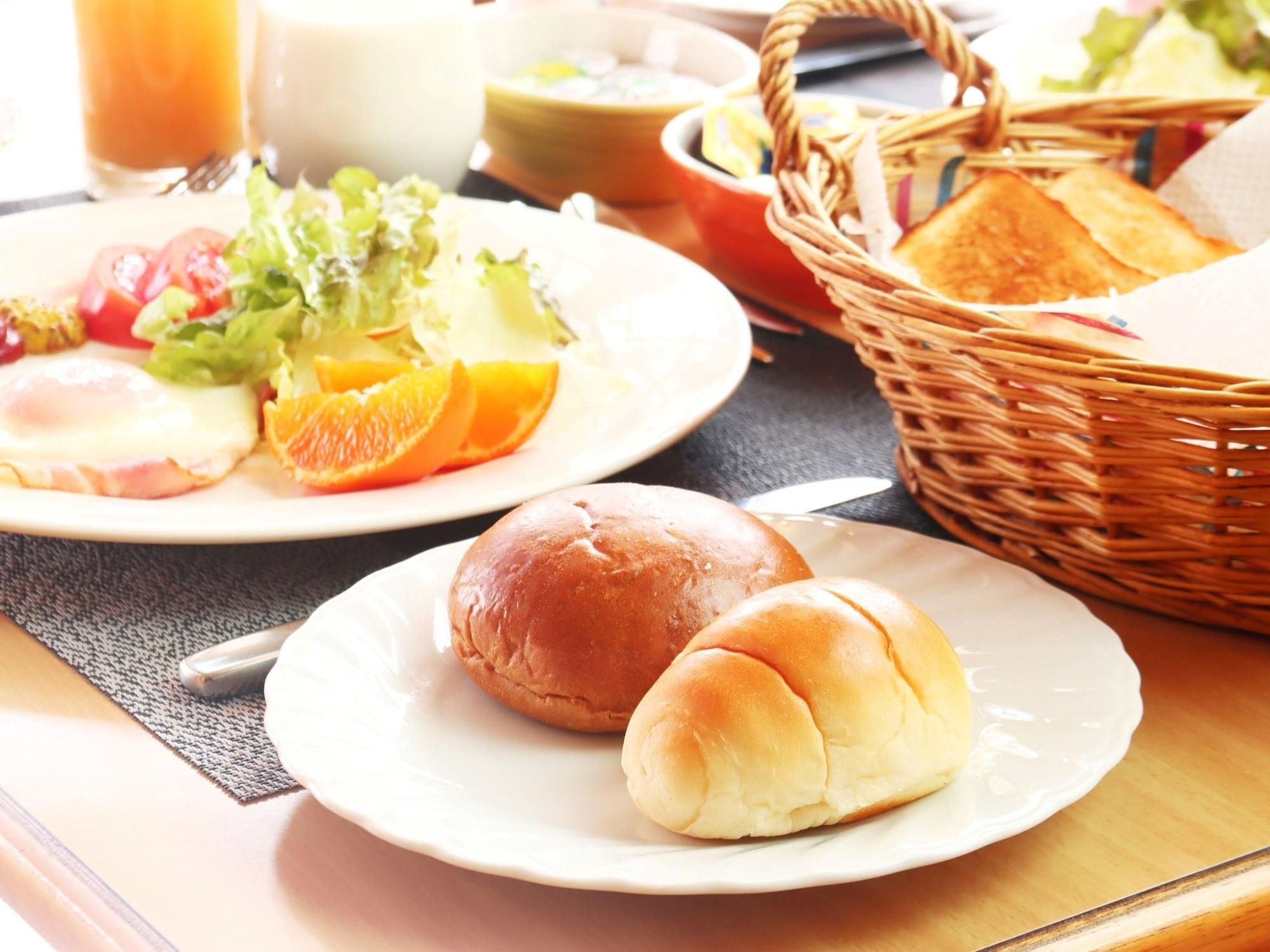 A breakfast setting with a plate of eggs, toast, and fruit, and a basket with bread.