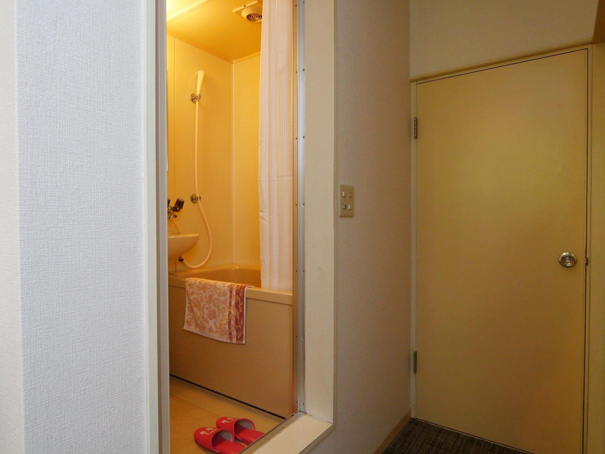 A small bathroom with a shower, a sink, and a towel hanging on the wall.