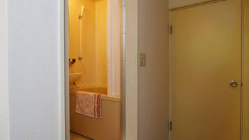 A small bathroom with a shower, a sink, and a towel hanging on the wall.