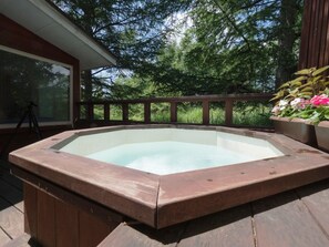 A hot tub on a wooden deck with a wooden railing and a window overlooking a forested area. - Guesthouse Curry Village (Kiryu)