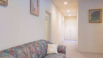 A hallway with a sofa, framed pictures, and a door leading to another room.